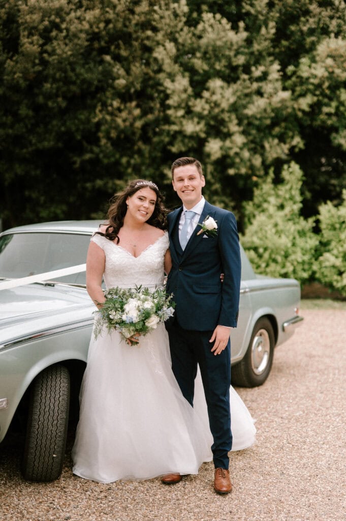 Bride and groom beside classic car