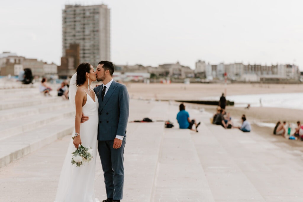 Wedding couple kissing on beach steps.