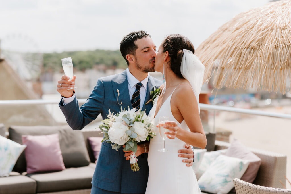 Bride and groom kiss with champagne and flowers
