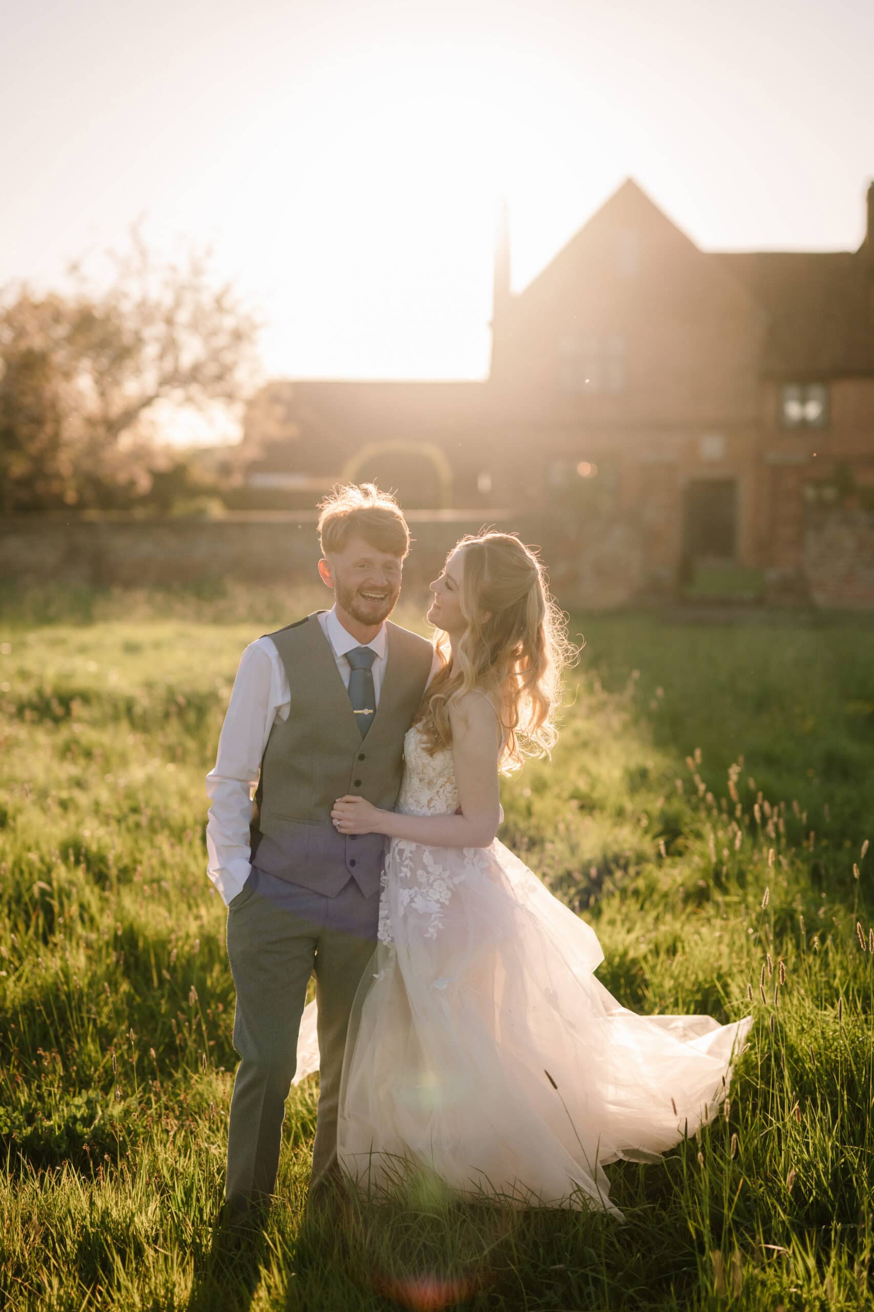 Bride and groom in sunlit field at sunset