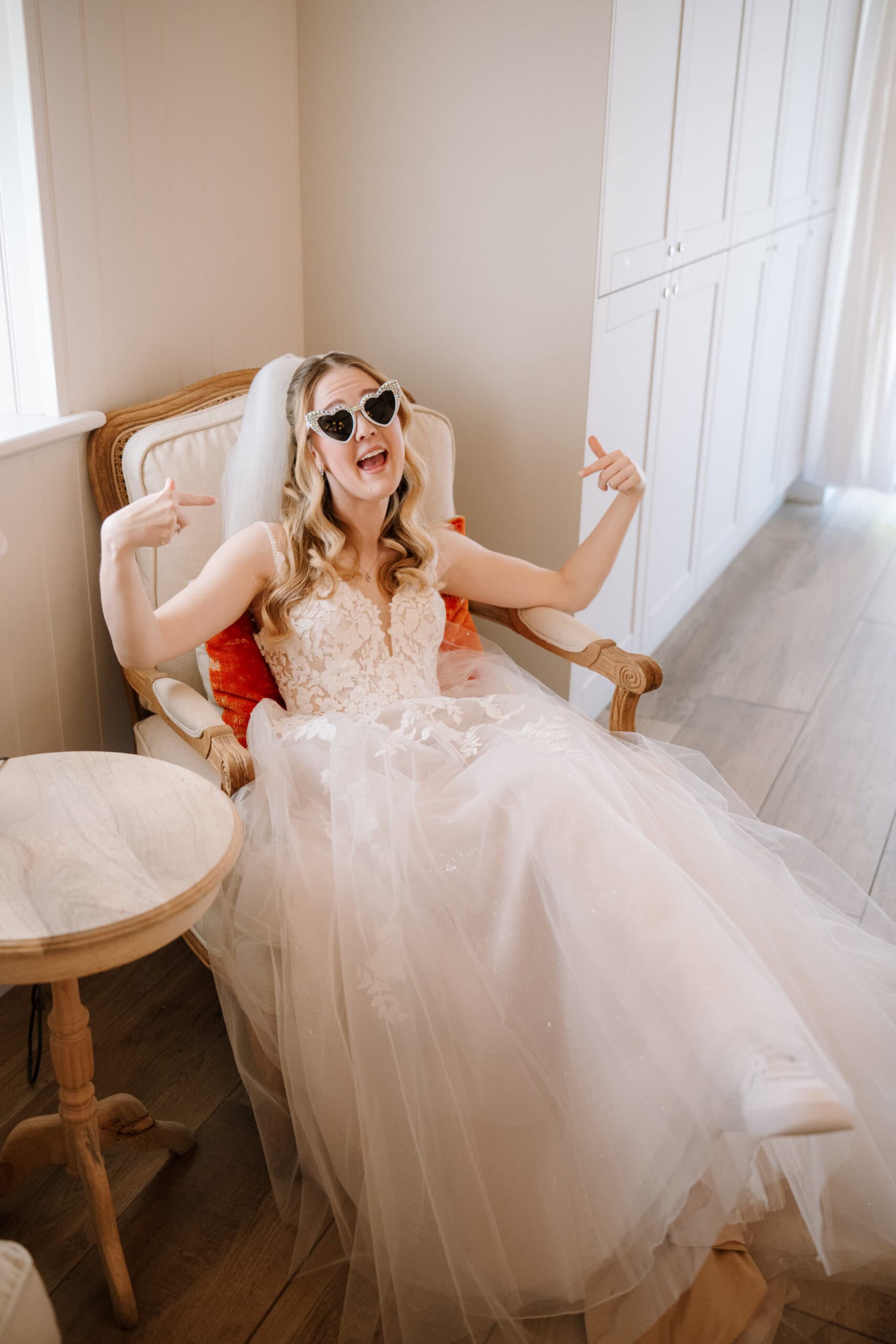 Bride in heart-shaped sunglasses sitting in armchair