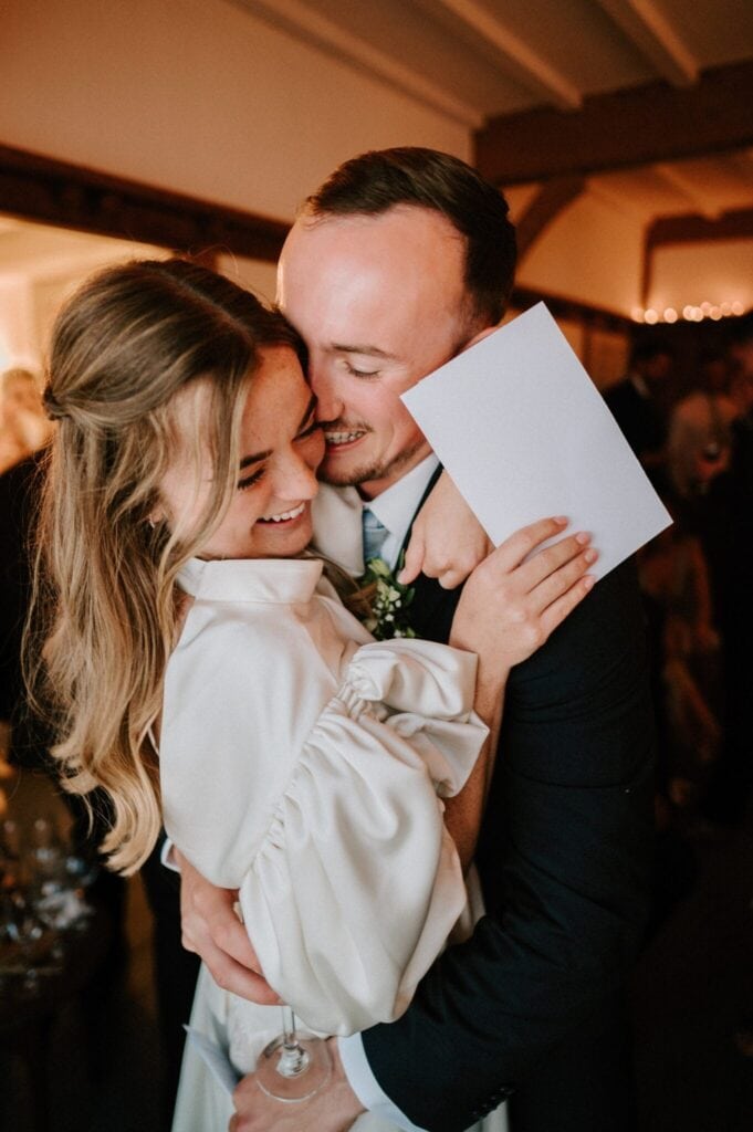 Newlyweds embracing and smiling at wedding reception