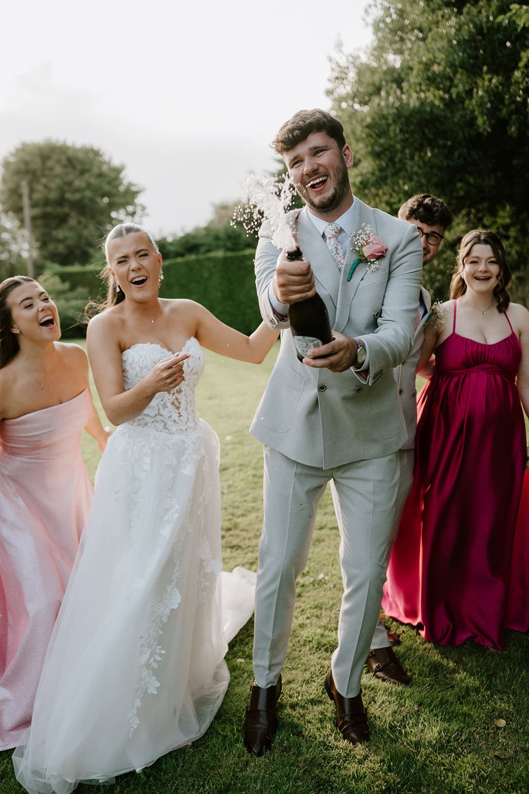 Groom popping champagne at outdoor wedding celebration