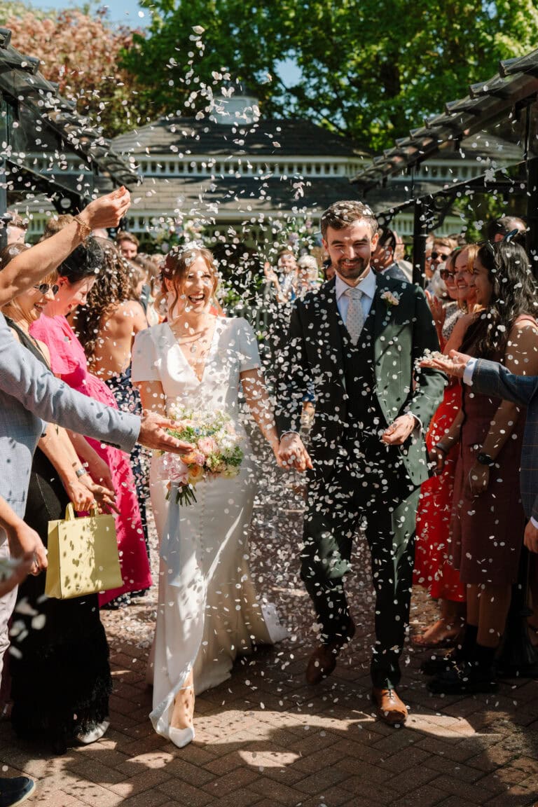 Bride and groom walking through confetti shower