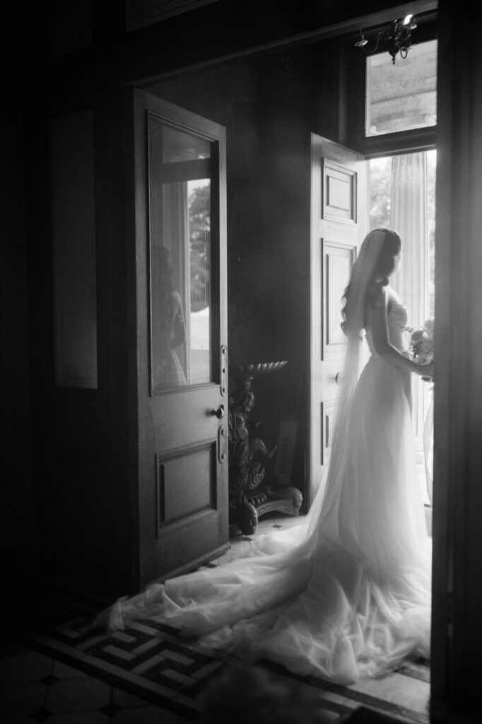 Bride in gown standing by open doorway