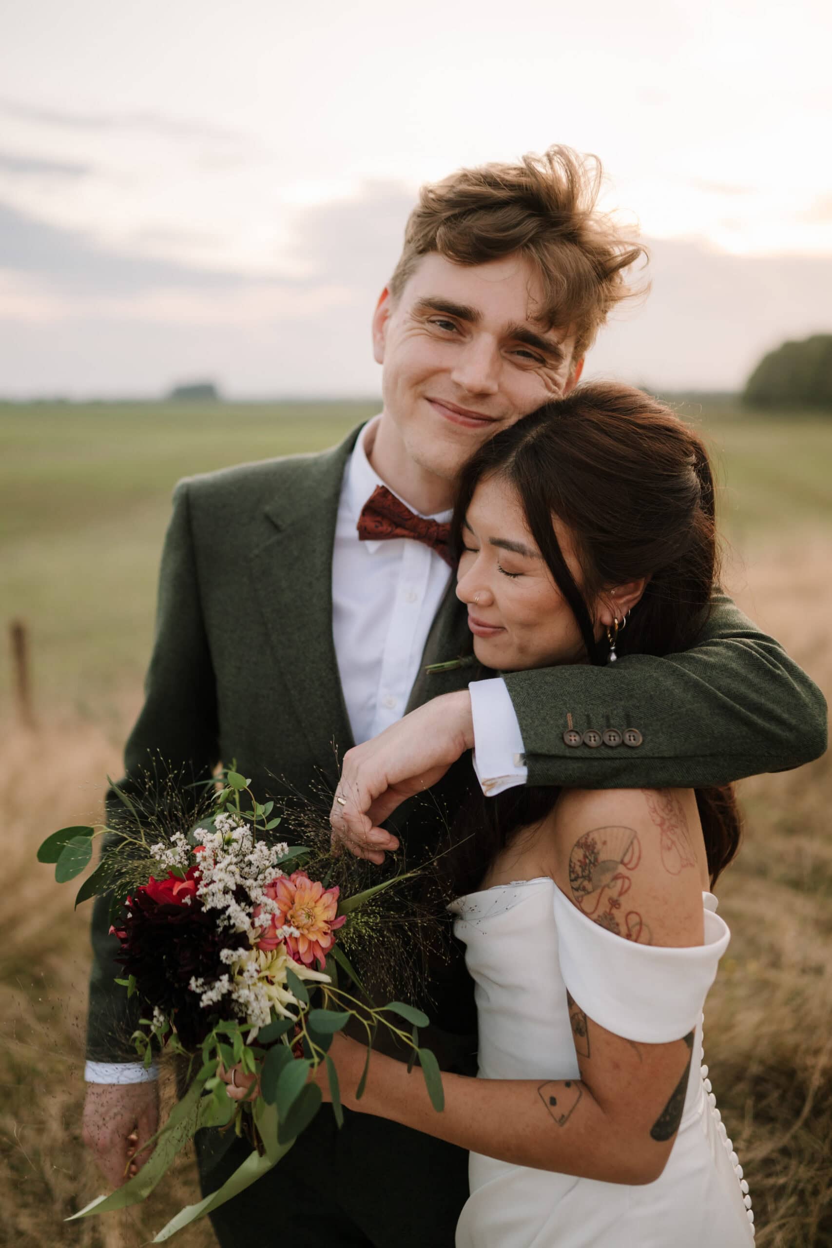Newlyweds embracing in countryside at sunset