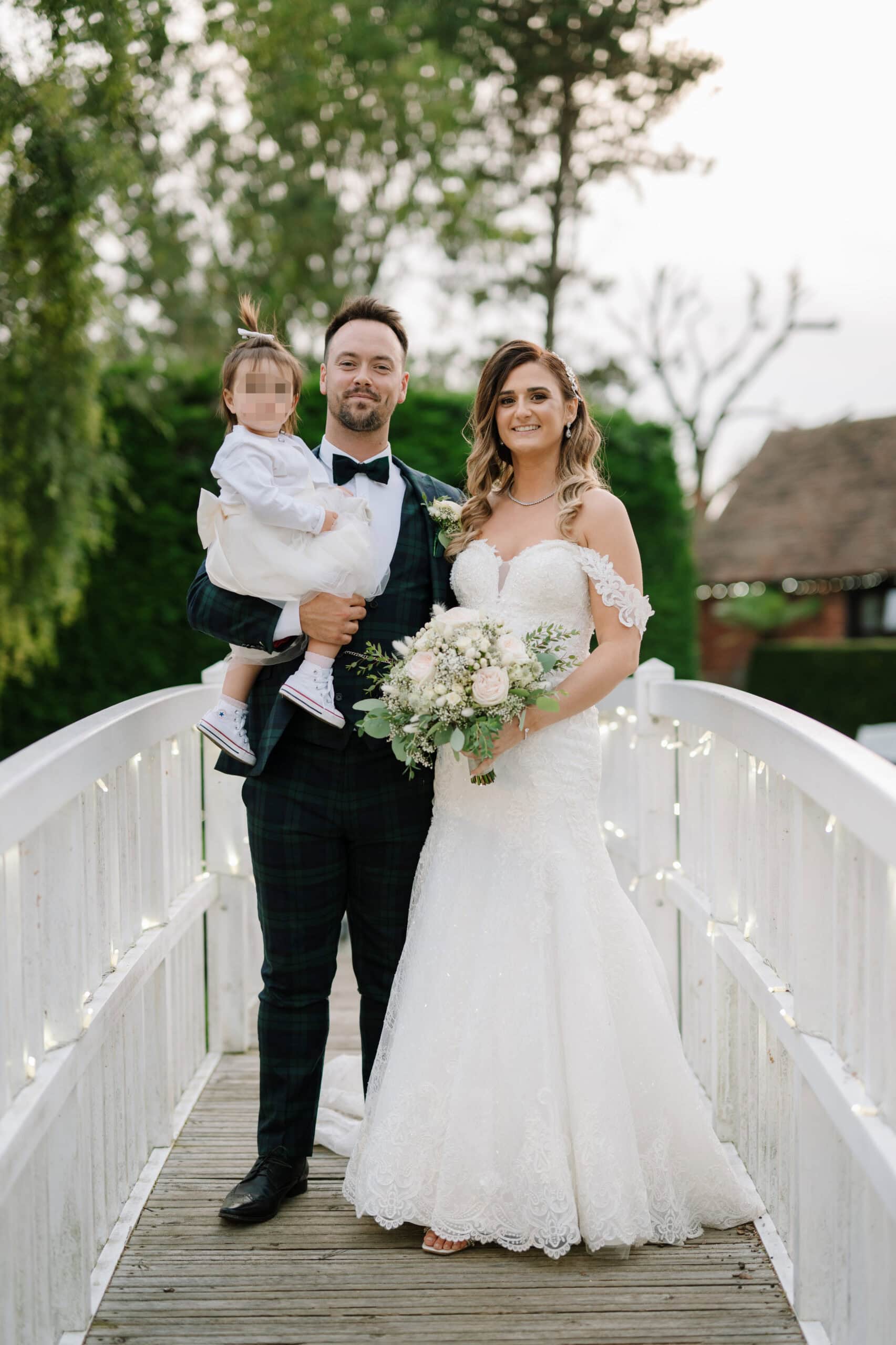 Bride and groom with child on garden bridge