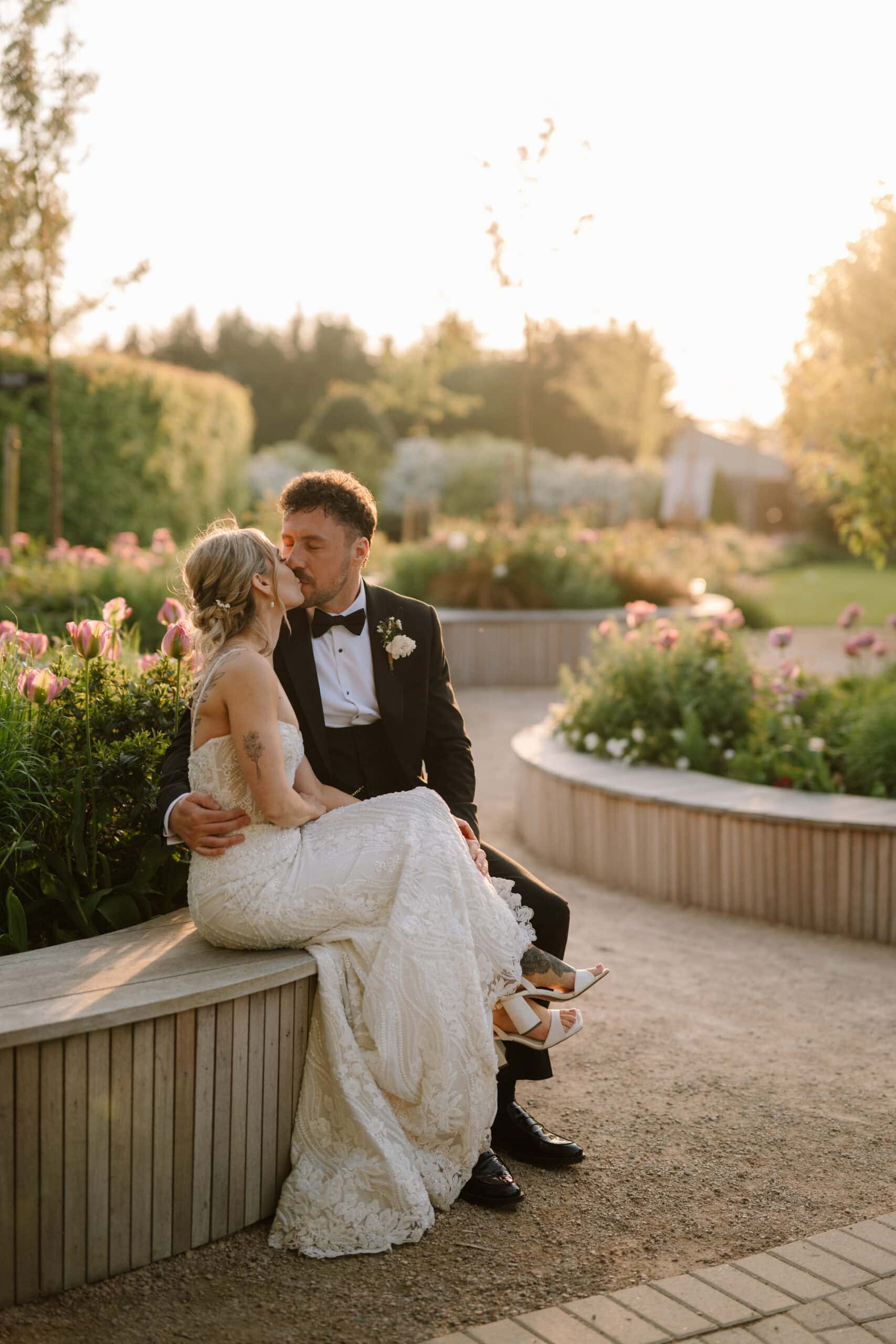 Bride and groom kissing in sunset garden
