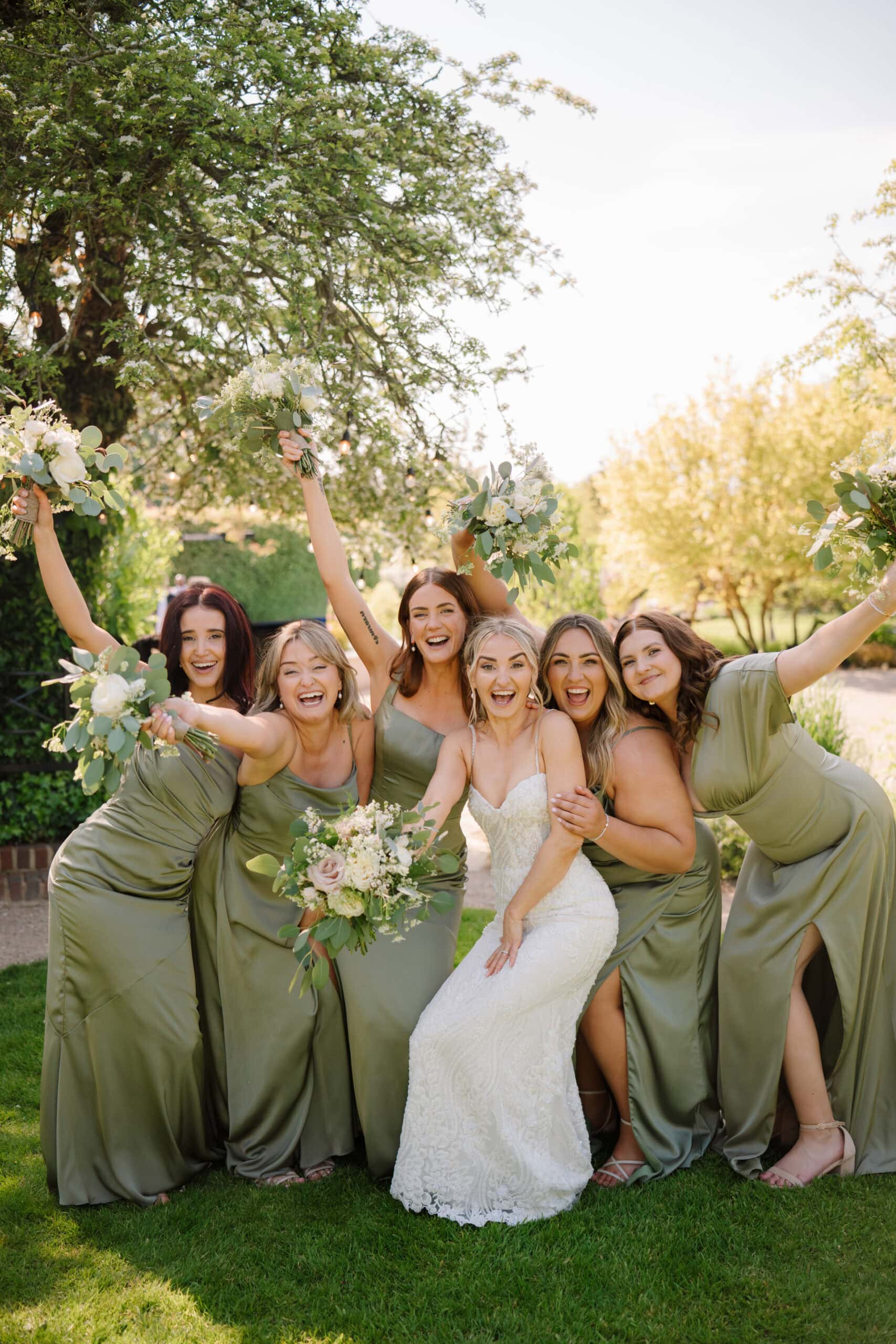 Bride and bridesmaids celebrating with bouquets outdoors