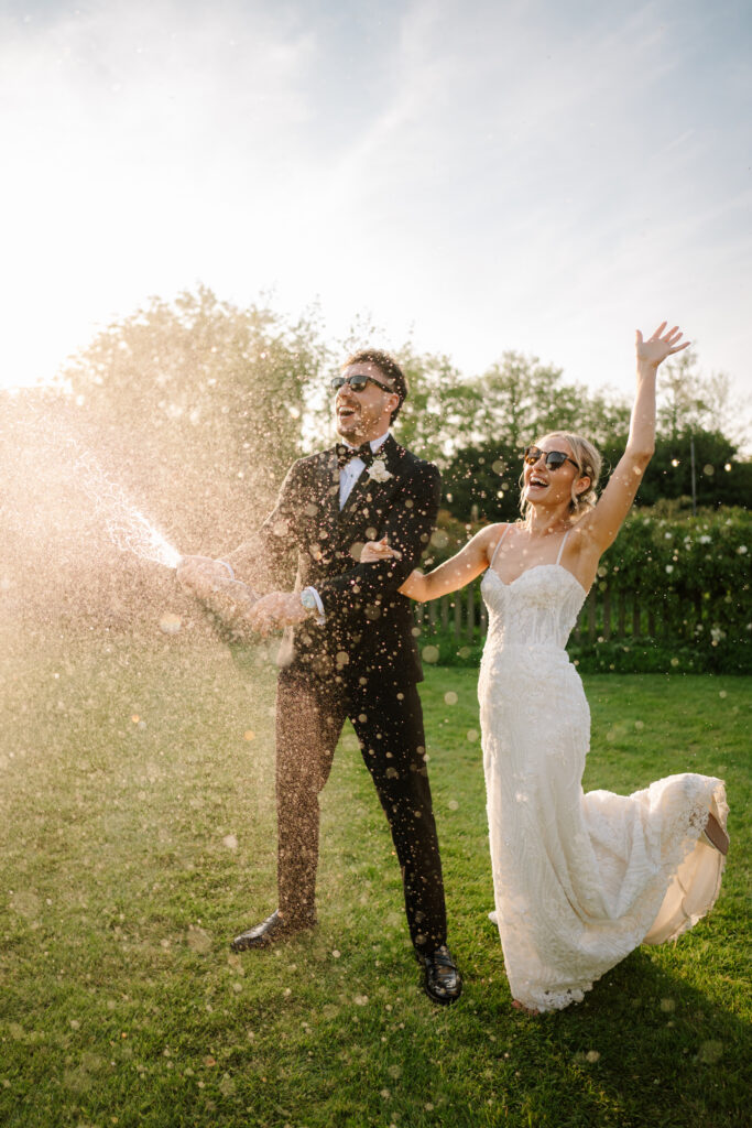 Bride and groom popping champagne outdoors