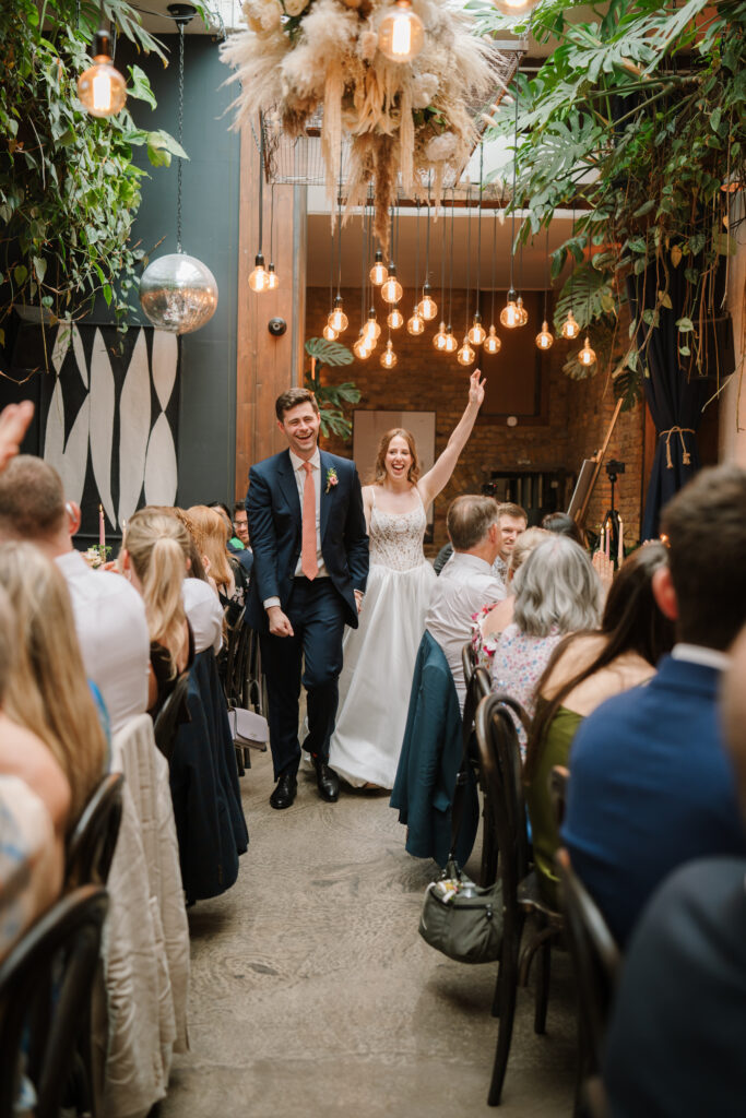 Bride and groom walking down wedding aisle indoors