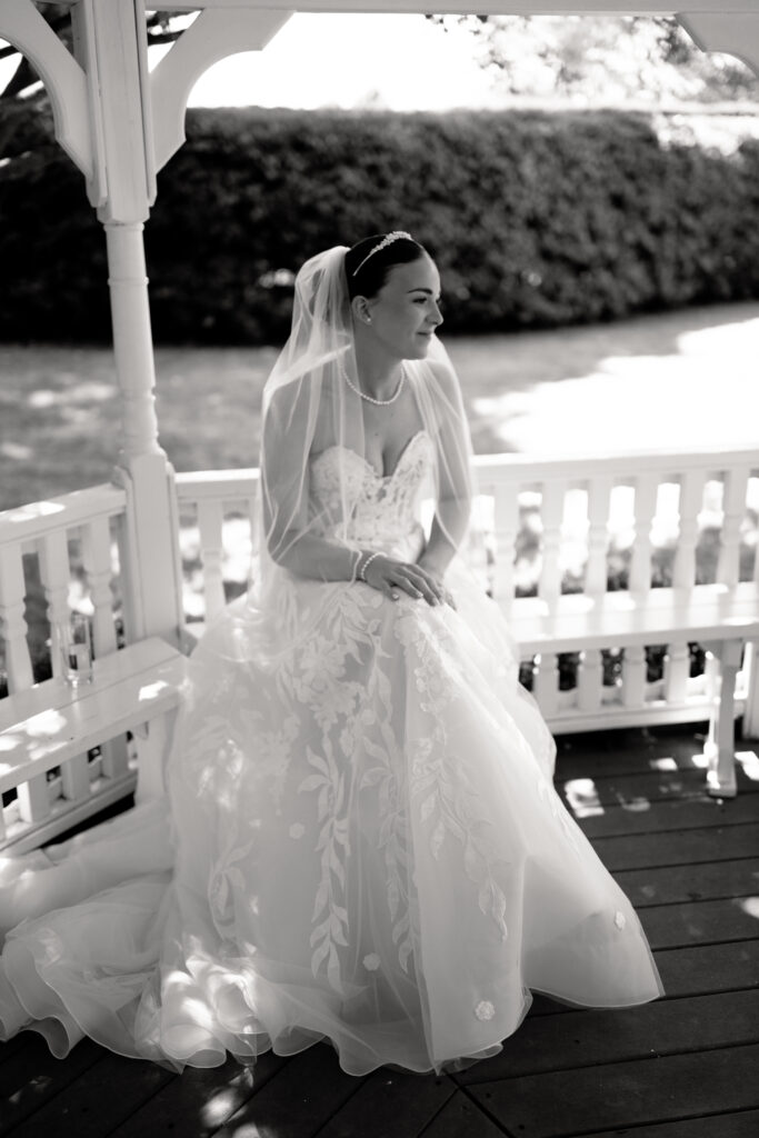 Bride in lace gown seated in gazebo outside at the old kent barn during wedding