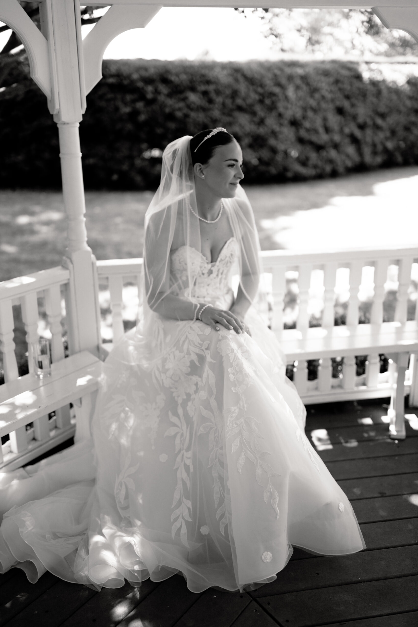 Bride in lace gown seated in gazebo outside at the old kent barn during wedding