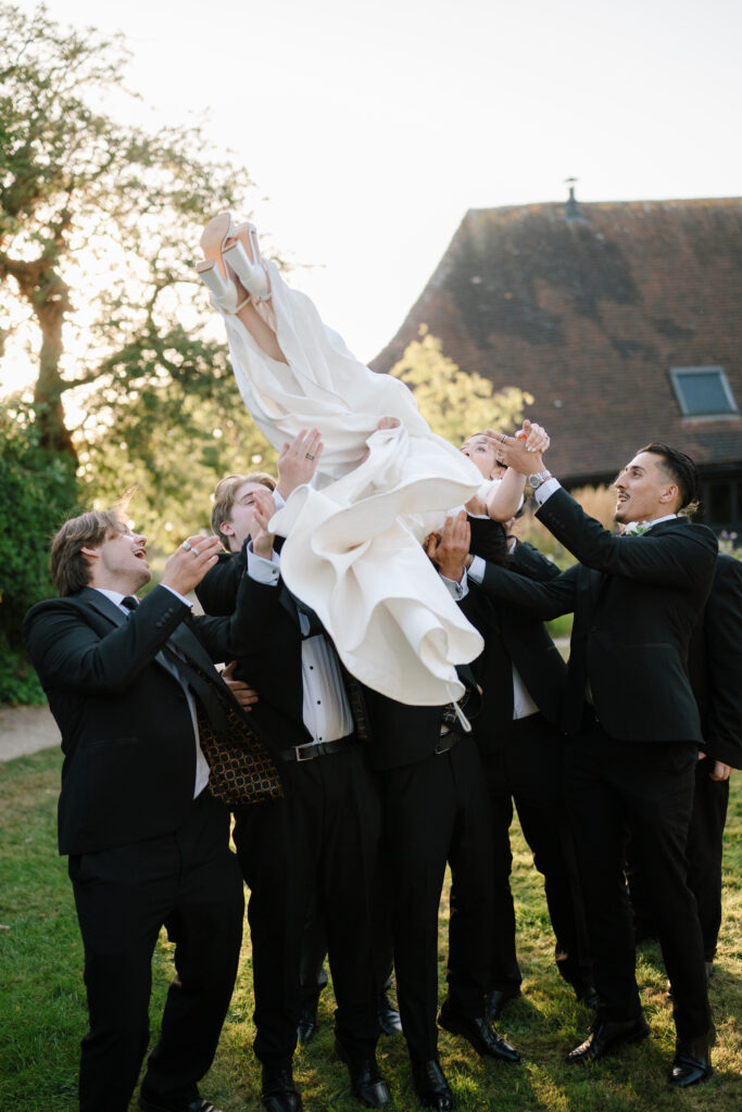 Bride tossed in air by groomsmen outdoors