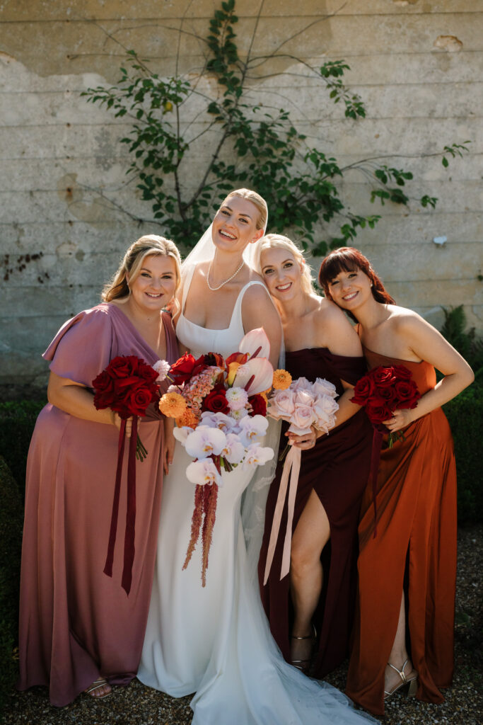 Bride with three bridesmaids holding colourful wedding bouquets on wedding day